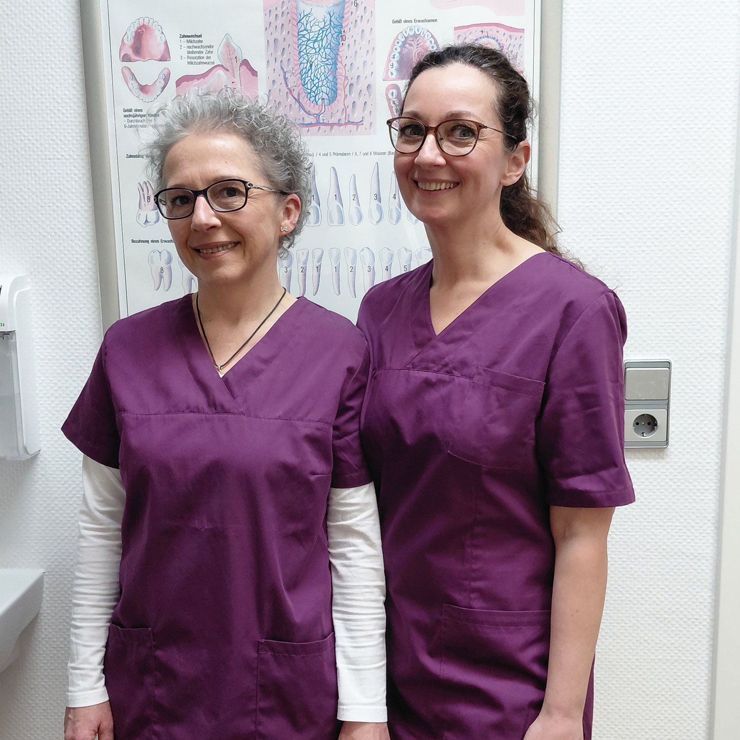 zwei Zahnmedizinische Fachangestellte mit lila Kleidung