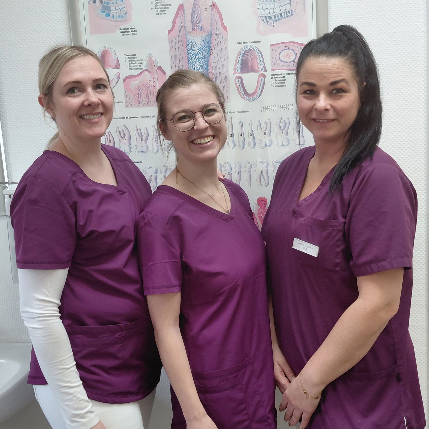 drei Zahnmedizinische Fachangestellte mit lila Kleidung